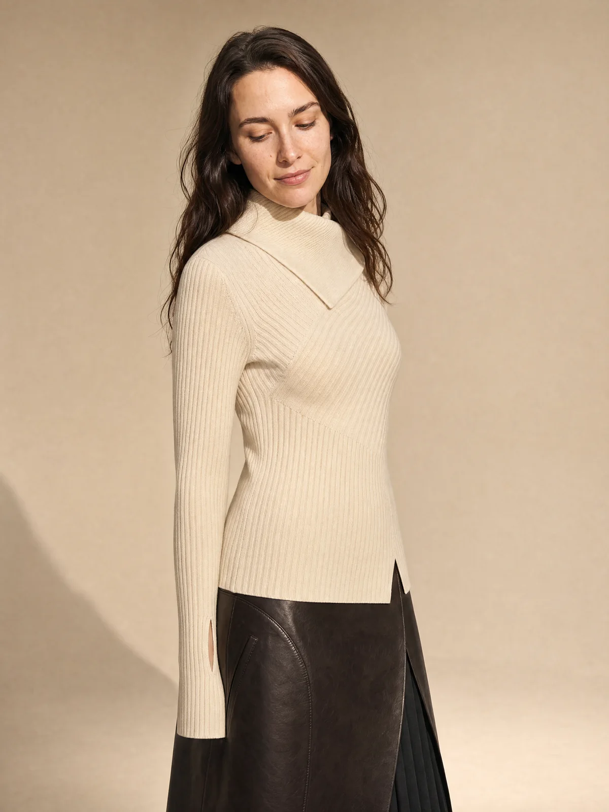 Profile on-model image of a ribbed cream knit with a leather wrap skirt