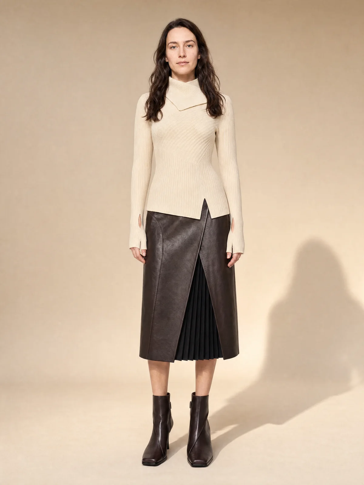 Seated on-model image of a ribbed cream knit with relaxed styling