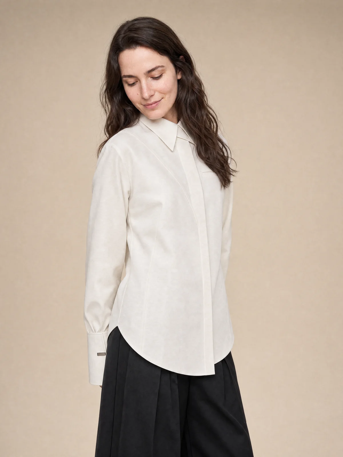 Seated on-model studio image of a cream collared shirt with a relaxed pose